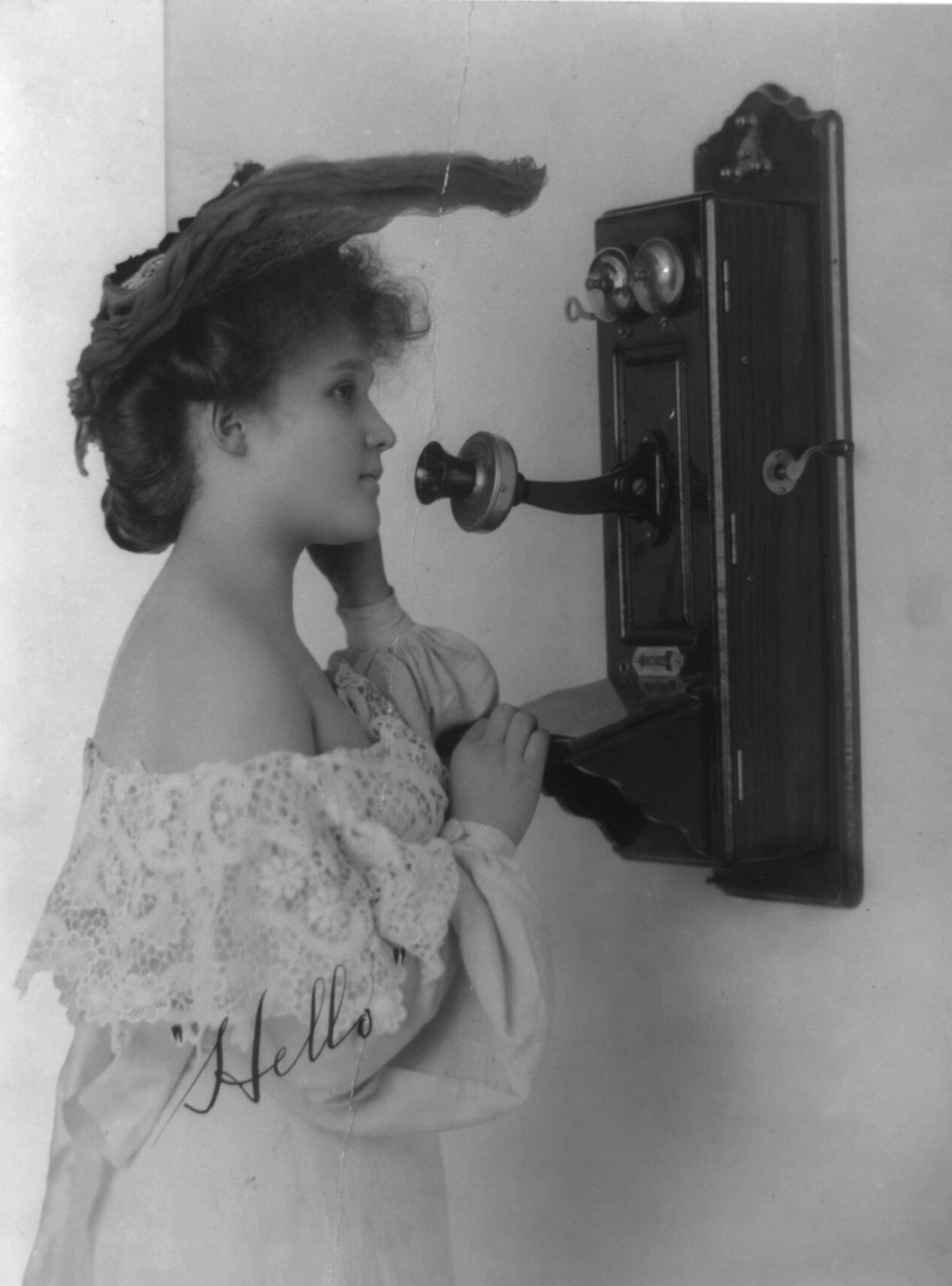 Woman speaking into wall mounted telephone, 1905